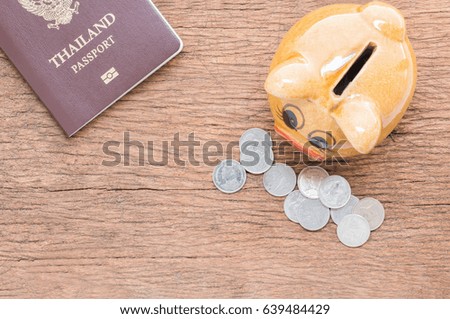 Pork piggy bank, money and passport on brown old wood floor, save for travel and leisure.