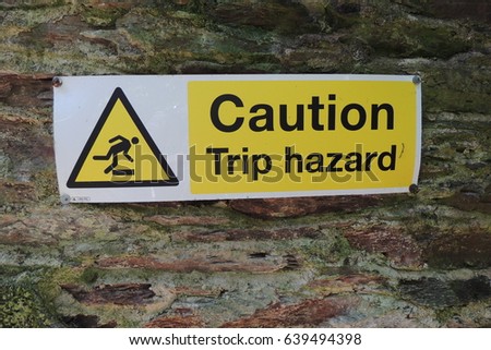 Caution Trip hazard - a sign on the wall of a derelict Victorian tea house, on the coastal path near Portwrinkle in southeast Cornwall
