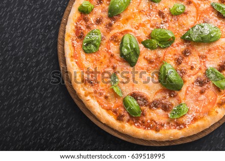 tasty pizza with basil and tomato on black table