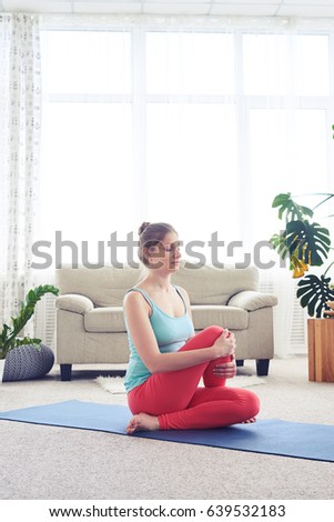 Side view of woman in fashionable tights doing yoga fish pose on yoga mat