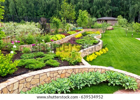 Landscape design with flower beds in home garden, beautiful landscaping in residential house backyard. Scenic view of nice landscaped garden, scenery of luxury back yard in summer. Nature theme. Royalty-Free Stock Photo #639534952
