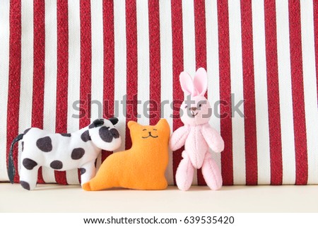 Cute rabbit and cat are standing with red and white fabric background