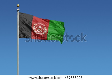Flag of Afghanistan on pole blowing in wind in front of a clear blue sky