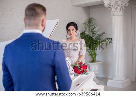The bride and the groom are standing near the piano