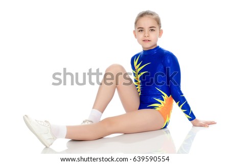 A charming gymnast girl, a younger school age, in a beautiful blue swimsuit, performs an exercise on the floor.Leaning elbows on the floor.Isolated on white background.