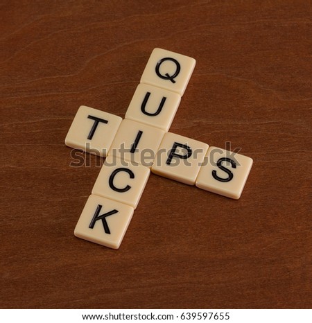Crossword puzzle with words Quick Tips. Travel guide concept. Ivory tiles with capital letters on mahogany board.
