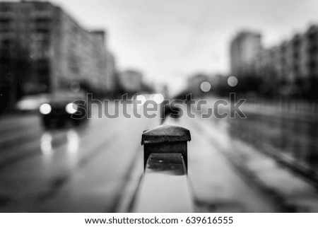 Rainy day in the big city, the headlights of the approaching car. Close up view, from the handrail on the sidewalk level, image vignetting and the black and white tones