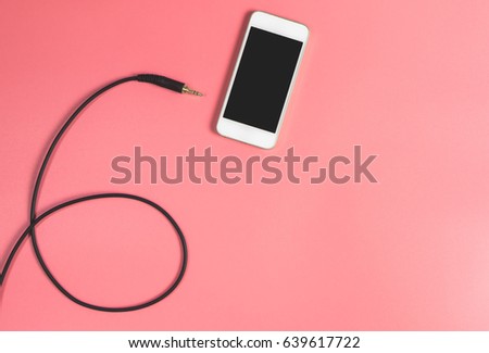 Blank smartphone with jack cable and pink copy space