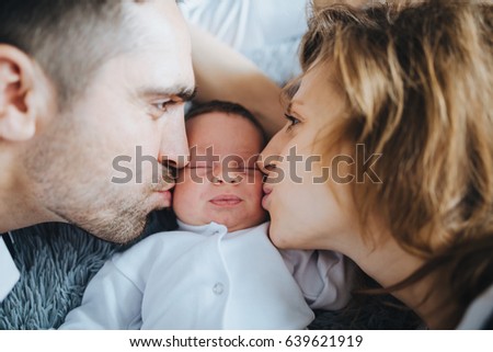 Loving parents kiss thir small newborn sleeping baby
