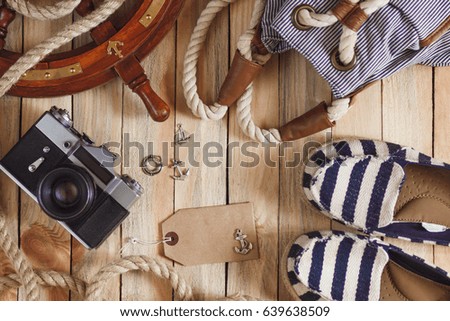 Striped slippers, camera, bag and maritime decorations on the wooden background, top view