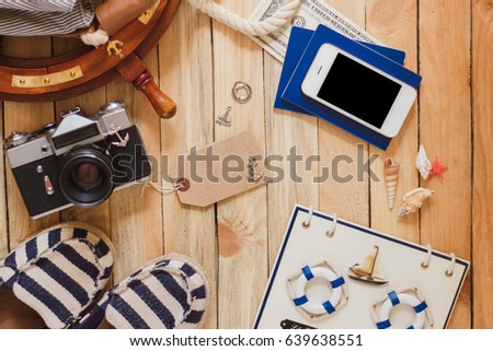 Striped slippers, camera, phone and maritime decorations on the wooden background, top view