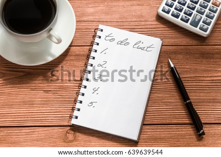 Text, to do list on a notepad with pen, coffee and calculator on a wooden table with copy space. Business cases, ideas, developments. Drawing up plans.