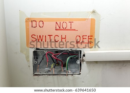 Dangerous and poor quality old electrical wiring with a sign taped up saying do not switch off