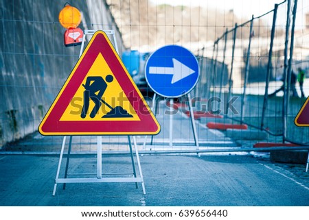 Work in progress. Roadworks, road signs. Men at work. Some signs signage for work in progress on urban street. Barriers and road signs. Silhouette of a worker at work. Right arrow.