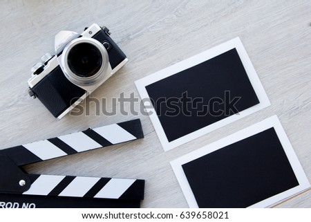 Movie production clapper board, vintage camera with photo cards with copy space against wooden background