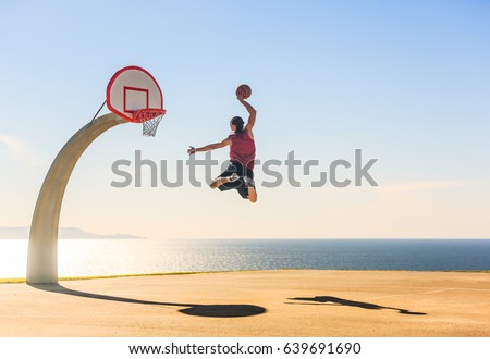 Basketball Player scoring an amazing slam dunk outdoors. Royalty-Free Stock Photo #639691690