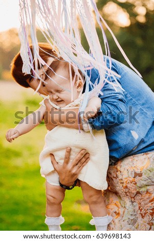 Ribbons hang over mother kissing her daughter tender