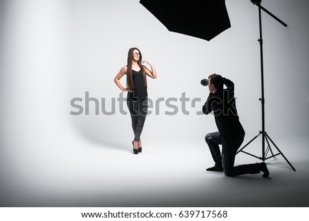 Beautiful young model is smiling and posing. the photographer is taking pictures with a digital camera