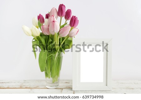 Tulip with blank picture frame on white wooden table