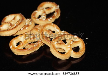 Sweet pretzel with sesame seeds isolated on black background