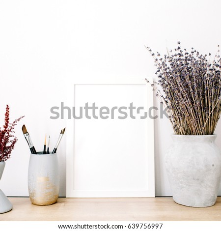 Front view blank mock up of photo frame with lavender bouquet and trendy stuff at white background. Minimalistic decorated home office concept.