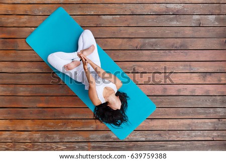 Top view of beautiful young fitness woman working out on wooden floor terrace, doing yoga exercise, full length