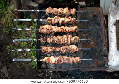 Spits with pieces of meat on the grill over hot coals, close-up top view