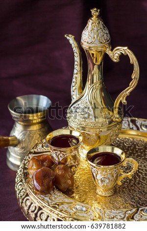 Traditional golden Arabic coffee set with dallah, coffee pot and dates. Dark background. Vertical photo.
