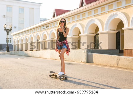 summer holidays, extreme sport and people concept - happy girl riding modern skateboard on city street