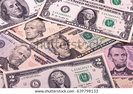Pile of dollar bills of different denominations on black background