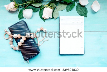 Spring background layout on a blue wooden background with flowers and rose petals daily planner sheets for notes and purse and beads accessories