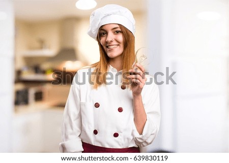 Happy Beautiful chef woman holding a bulb in the kitchen