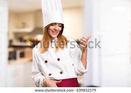 Beautiful chef woman making guitar gesture in the kitchen