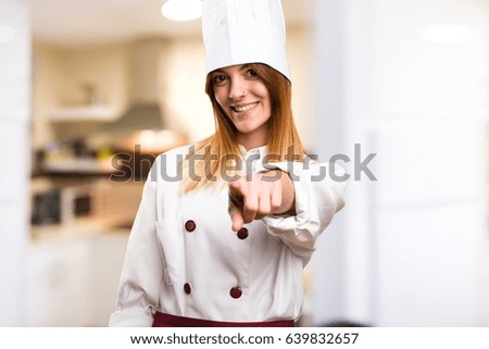 Beautiful chef woman pointing to the front in the kitchen