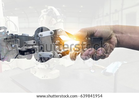 Cyber communication and robotic concepts. Industrial 4.0 Cyber Physical Systems concept. Double exposure of Robot and Engineer human holding hand with handshake and automate robot arm background. Royalty-Free Stock Photo #639841954