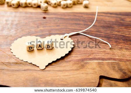 Father's Day - Dad on cardboard heart on wood grain background

