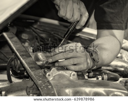 Man at work in a garage. Auto mechanic worker in car repair service. Image of mechanic hands with a tool. Auto repair concept. Close up. Black White vintage. Nice background for your text. Matte 