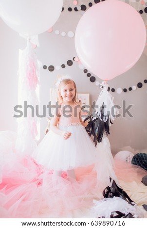 Beautiful little blonde girl celebrating birthday party with big bouncy balls. Family celebration of the child