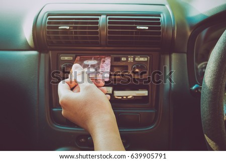 Woman hand holding tape cassette in car for driving listen music - vintage color tone effect. Royalty-Free Stock Photo #639905791