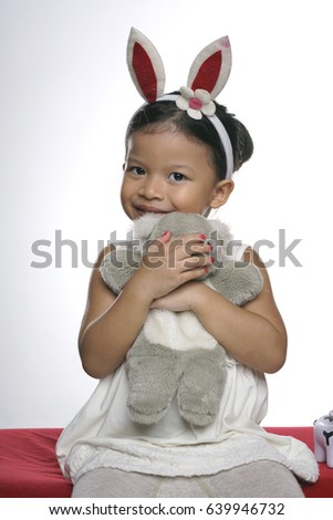 Lifestyle studio shot of a female Asian girl or toddler with her toys, on semi-white background