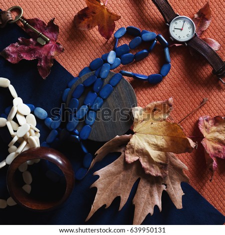 Autumn theme flat lay of leaves and fashion accessories on orange and navy