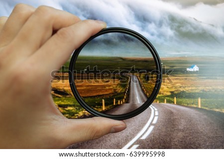 CPL filter held against the country road giving clarity Royalty-Free Stock Photo #639995998