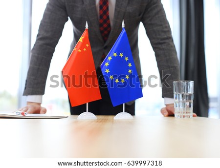 Chinese flag and flag of European Union with businessman near by
