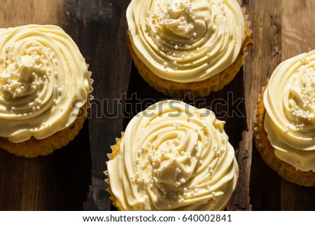 Cream colored cupcakes on a wooden board.  