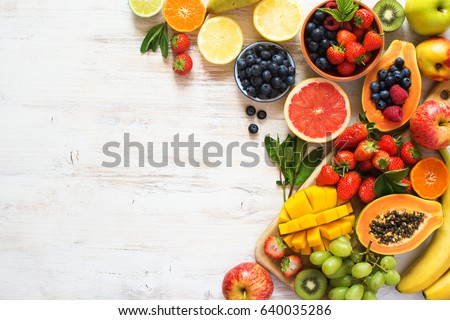 Above view of colorful fruits, strawberries, blueberries, mango, orange, grapefruit, banana, apple, grapes, kiwis on the white background, copy space for text, selective focus Royalty-Free Stock Photo #640035286