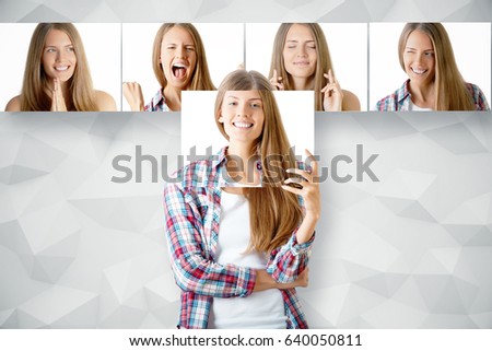 Young european girl hiding herself behind poster with smiling face. Row of faces with different expressions in the background. Emotion concept