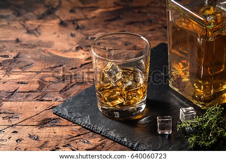 Whiskey with ice in glasses on rustic wood background, copy space