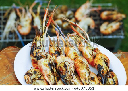 Stock Photo - close up grilled prawns in dish with stove charcoal background