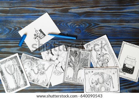 Many postcard in doodling style with drawn picture and inscription in russian "Potions from whims", "I was given a little elephant" on wooden blue background. Hand drawn, creativity, ideas. Top view.