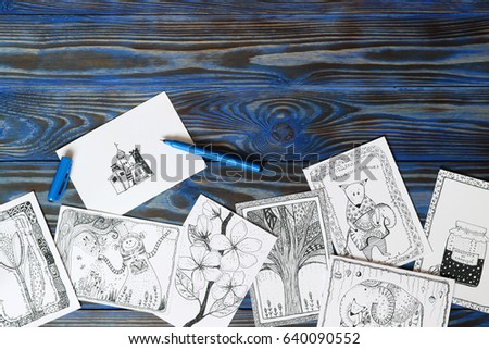 Many postcard in doodling style with drawn picture and inscription in russian "Potions from whims", "I was given a little elephant" on wooden blue background. Hand drawn, creativity, humor Top view